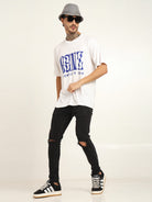 Man wearing oversized bamboo T-shirt with graphic design, black ripped jeans, and stylish sneakers, showcasing streetwear style.